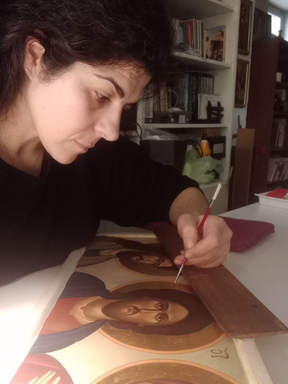 Iconographer Concetta Basile painting the face of Christ by hand with a brush on a gold-ground icon